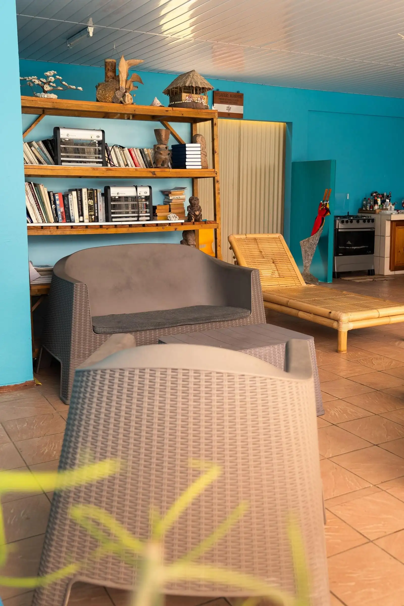 Pension library corner with wooden shelves, rattan armchairs and a blue wall