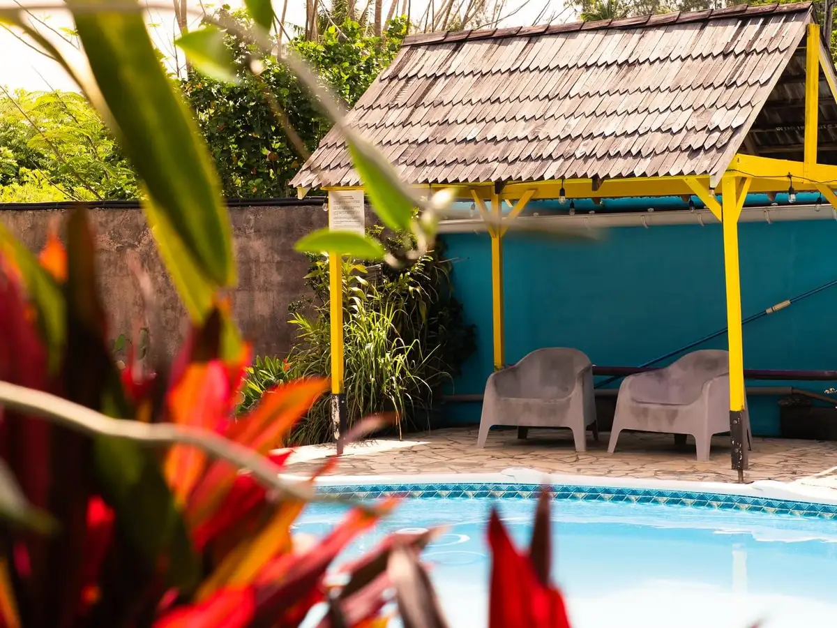 Jardin tropical de la pension avec plantes rouges et piscine, Huahine